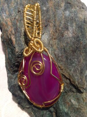 Pendant Pendant with a pink banded agate puffy coin. This can be made with any gemstone with simple wirework or more intricate woven wirework. All pendants are £15 and can be supplied with a chain or silk cord.